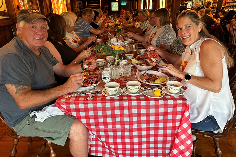 Smiling rows of people at table enjoying a Lobster Feast.