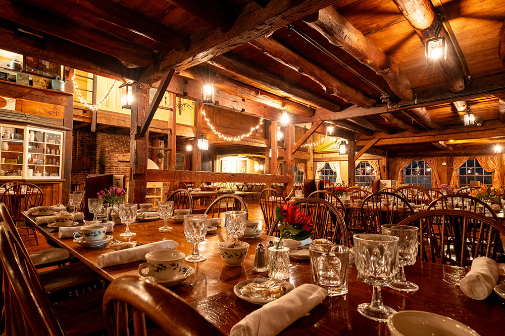 propertybarn A low-angled shot of set dining room tables with warm lighting and lanterns.