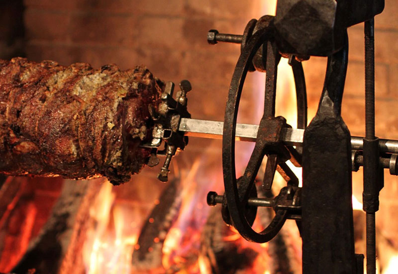 fplaceFeastInset2 Closeup of the Roasting Jack with spitted meat cooking over an open fire.
